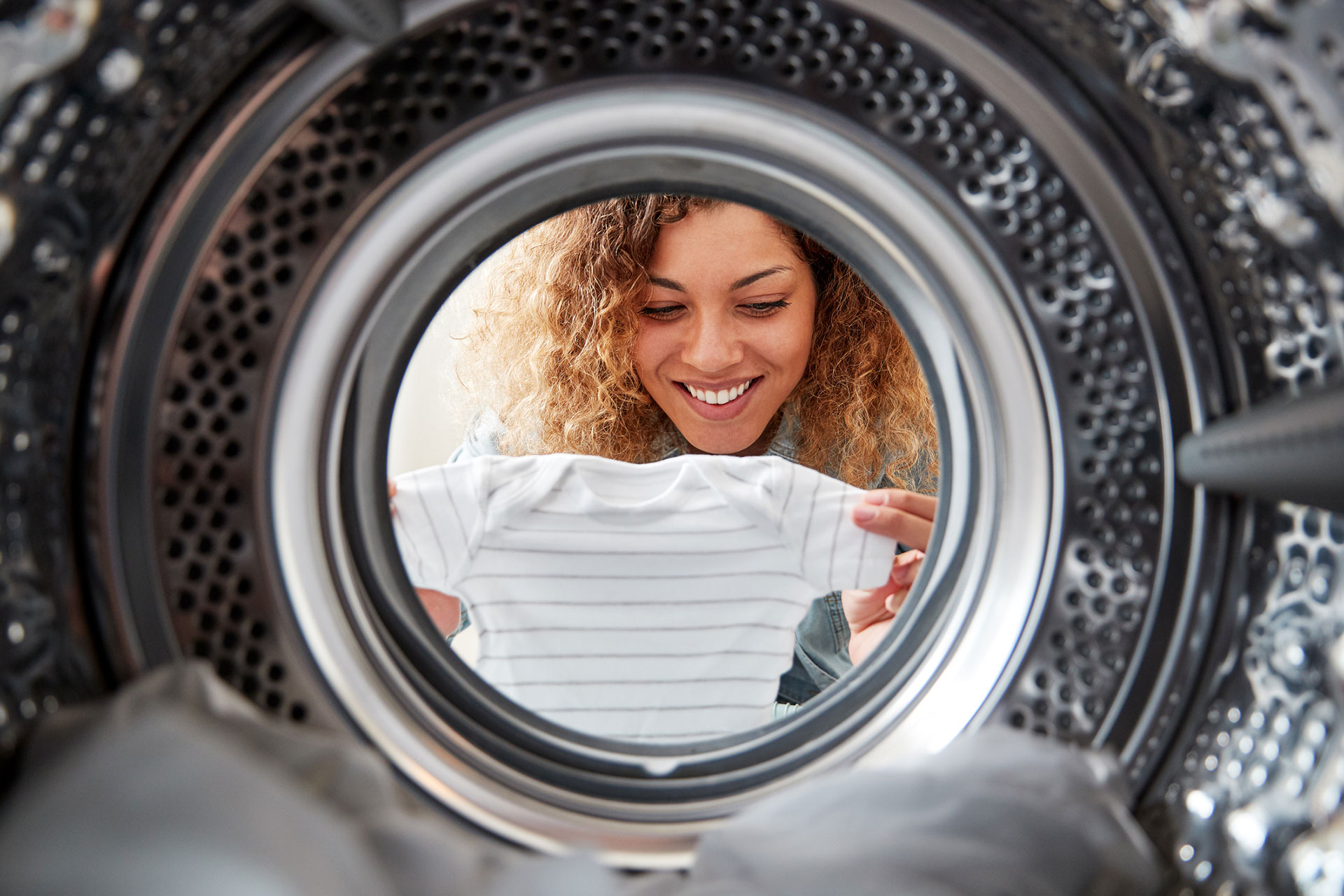 A Woman Takes Out Baby Clothes from a View Looking Out From Inside Washing Machine in a Largo, FL Laundromat